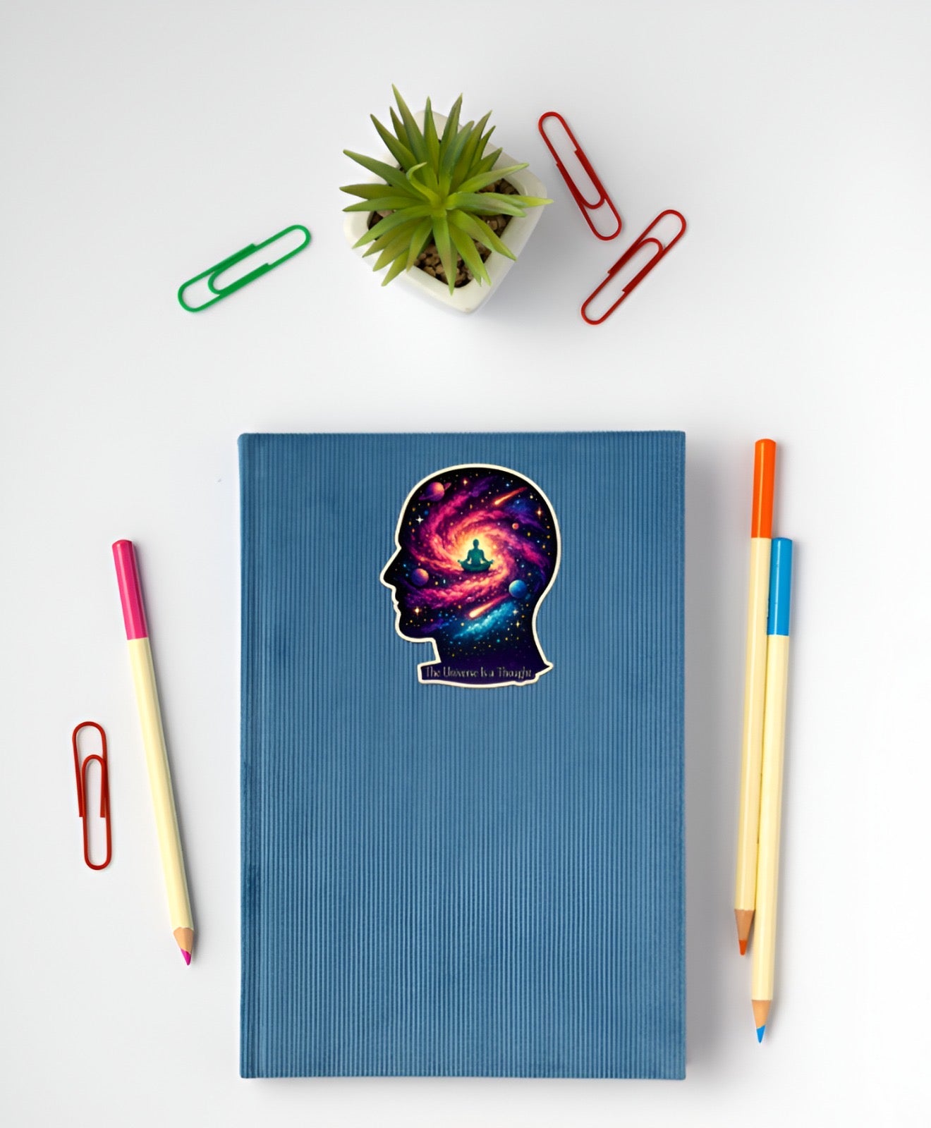 Blue notebook with a colorful brain design on a white surface with stationery items.