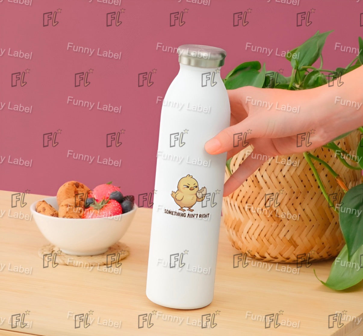 White water bottle with 'FL' branding held by a hand on a wooden surface with a bowl of snacks and plant.