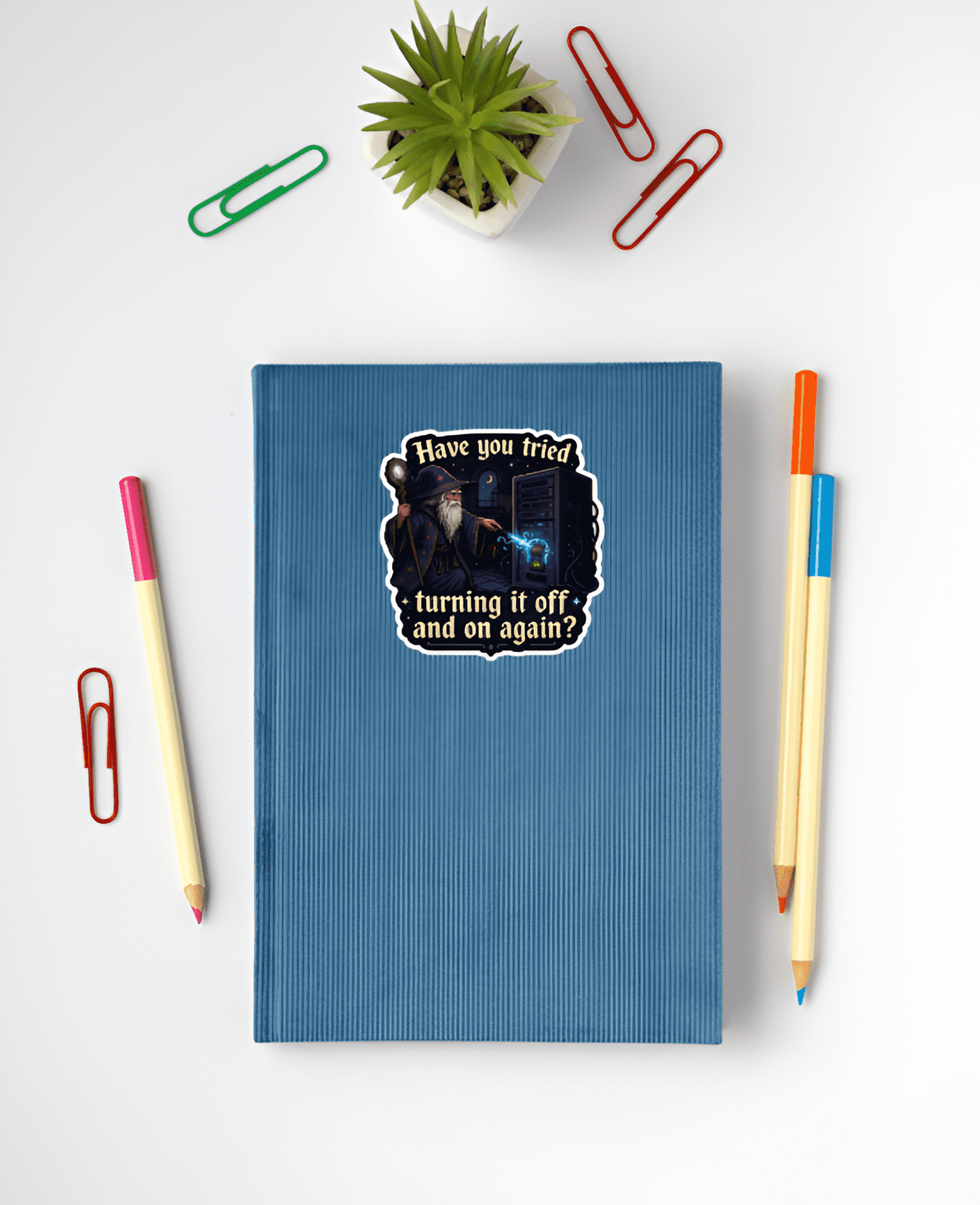 Blue notebook with a sticker on a white surface with stationery items