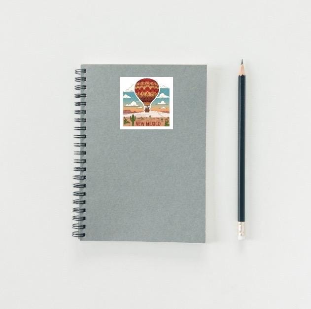 Gray notebook with a New Mexico-themed sticker and a pencil on a light gray background
