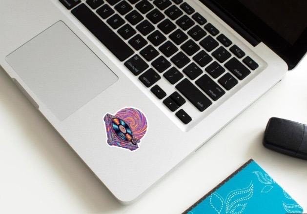 Laptop with a colorful sticker on a white surface