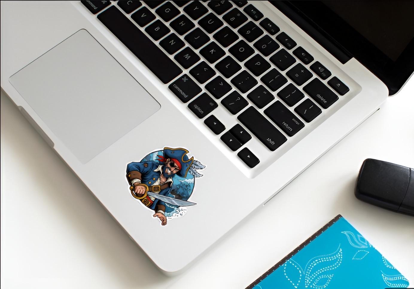 Laptop with a decorative sticker on the palm rest area, next to a mouse and notebook.