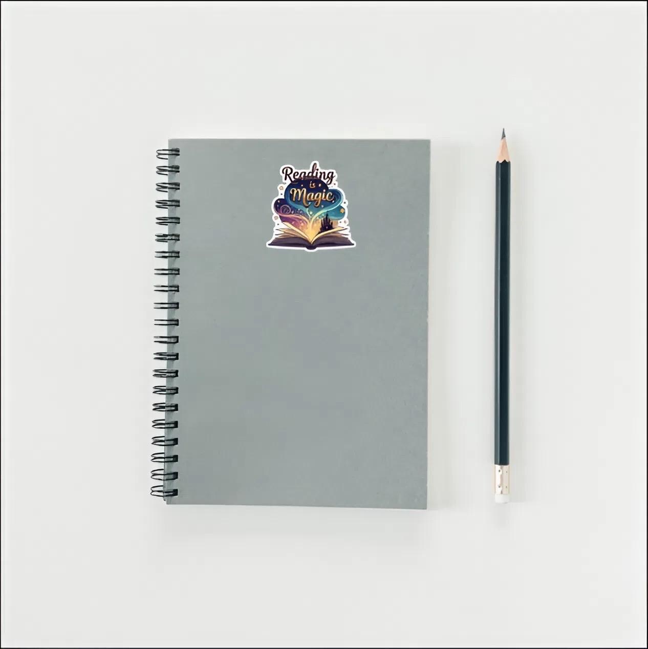 Gray spiral-bound notebook with a colorful sticker and a black pencil on a light gray background
