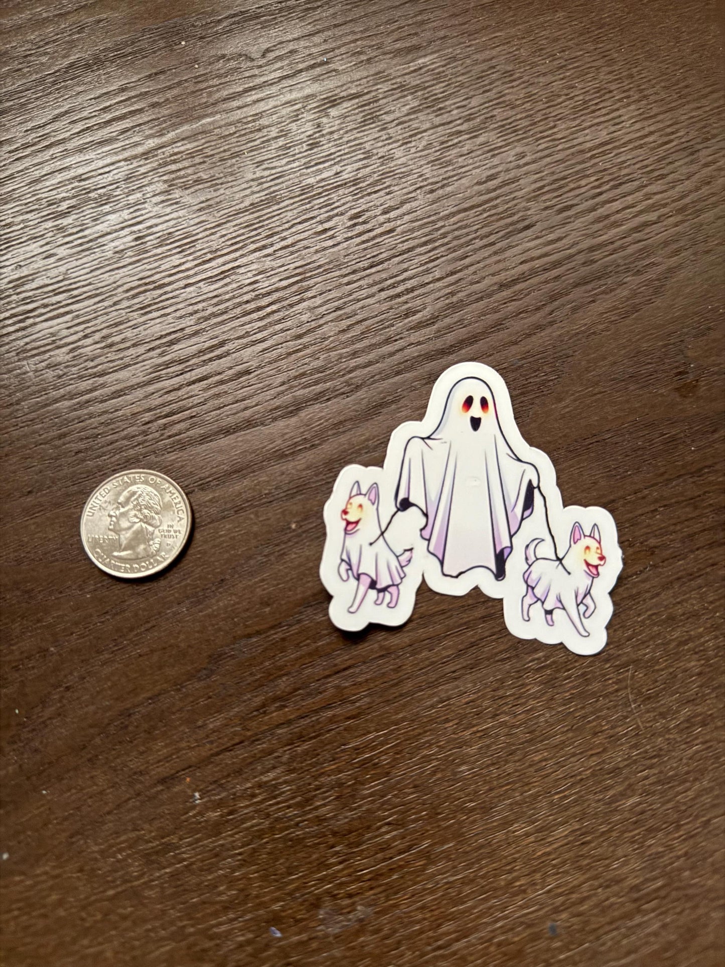 Ghost stickers with dogs on a wooden surface next to a coin for scale.