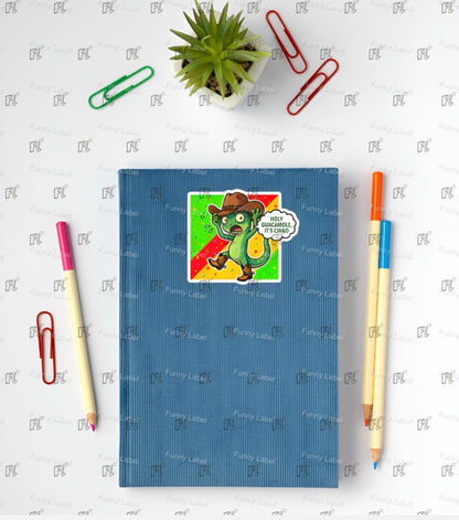 Blue notebook with a sticker of a dinosaur and a speech bubble, surrounded by stationery items on a light gray background.
