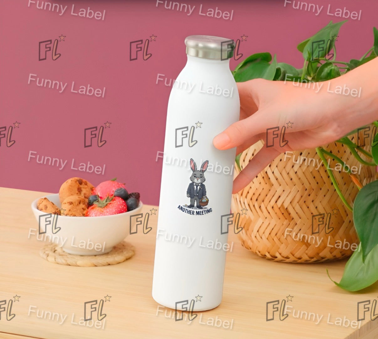 White water bottle with cartoon character and 'FL' branding held by a hand on a wooden surface with a pink background.