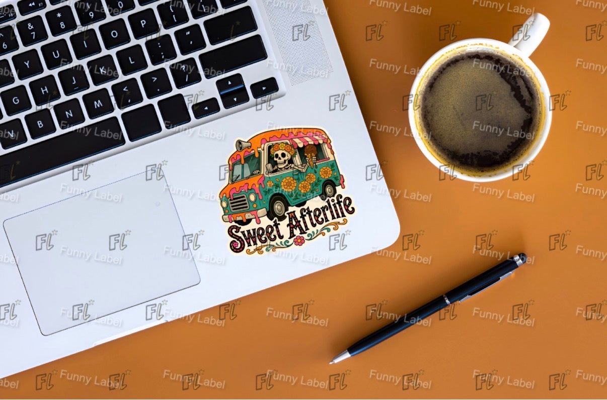 Laptop with a 'Sweet Afterlife' sticker, coffee cup, and pen on a brown surface.