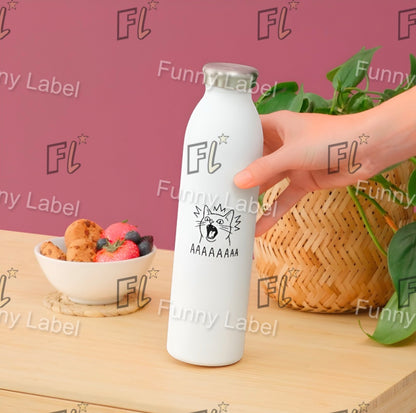 White bottle with 'FL' label held by a hand on a wooden surface with a bowl of fruit and a basket in the background.