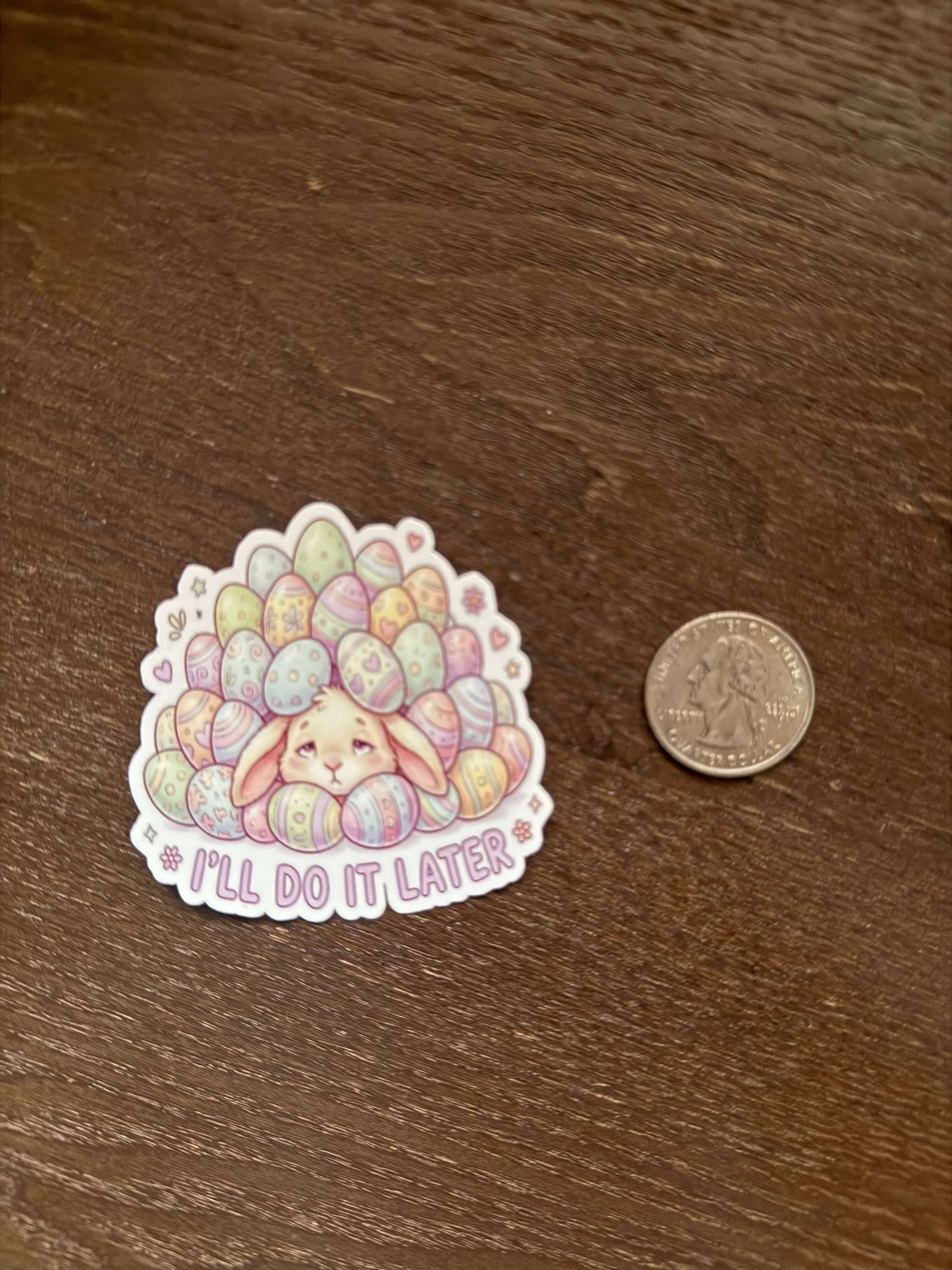 Sticker with colorful design and text 'I'll do it later' next to a coin on a wooden surface