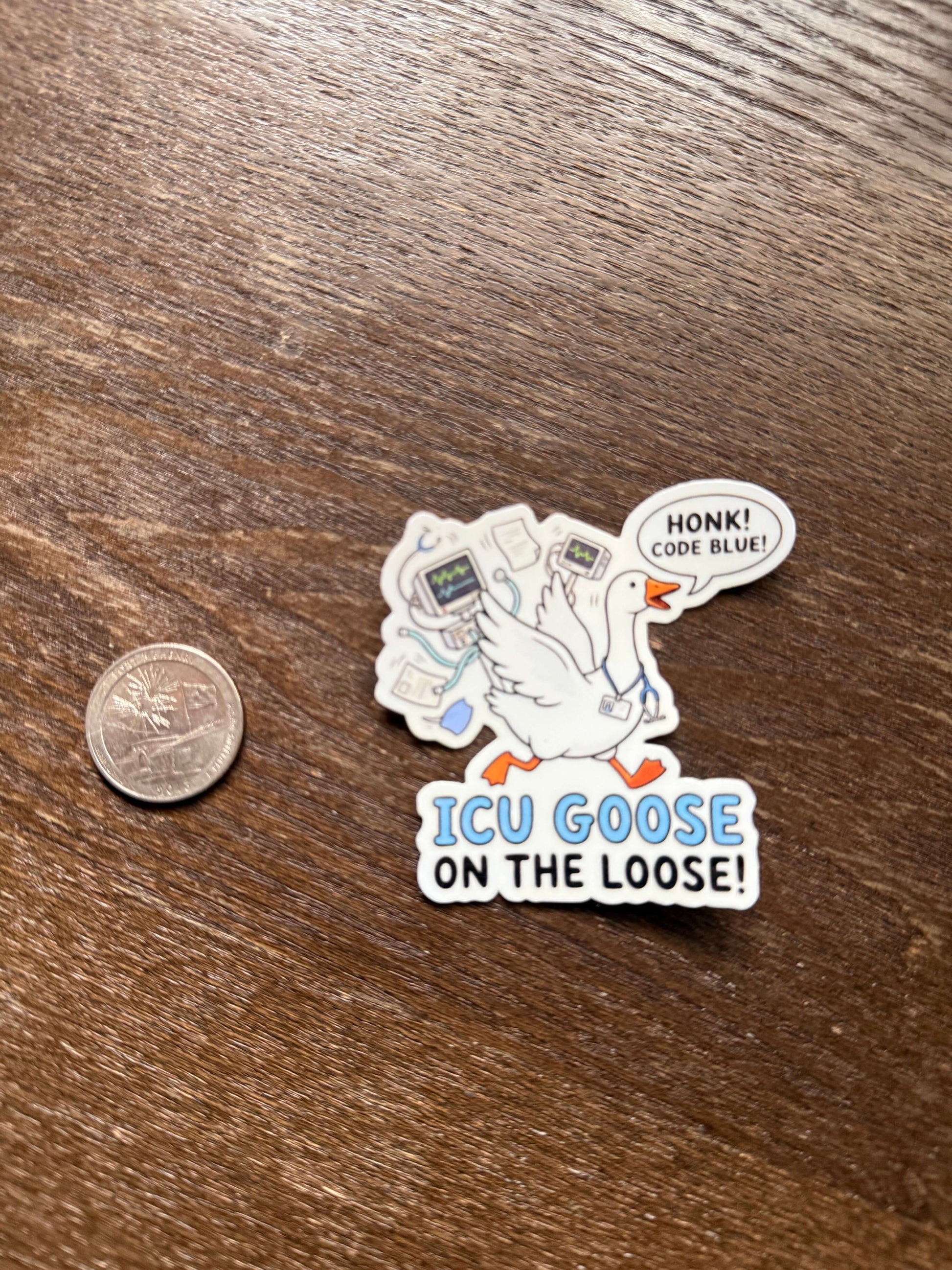 Sticker with a goose design and text on a wooden surface next to a coin for scale.