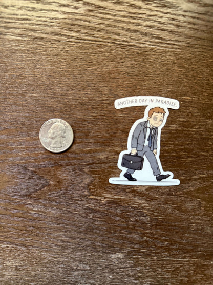 Sticker of a person lying on a bed with a coin for scale on a wooden surface