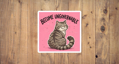 A flat, square vinyl sticker based on image.png featuring a charming cartoon illustration of a smug grey tabby cat sitting down and looking backward with a defiant, self-satisfied smile on a solid pink background under the bold arched text "BECOME UNGOVERNABLE".