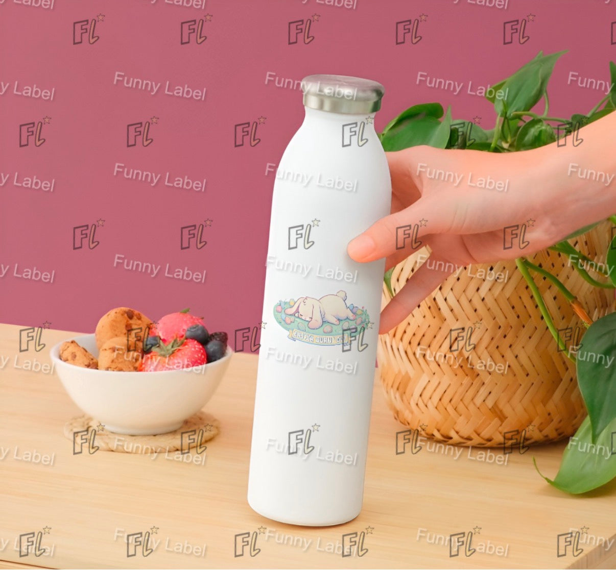 White water bottle with 'FL' branding held by a hand on a wooden surface with a bowl of snacks and a plant.