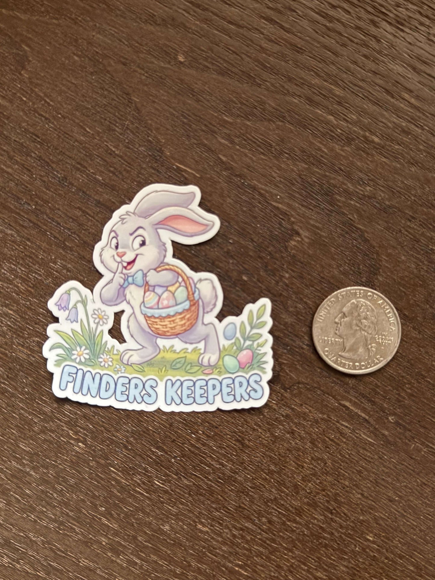 Sticker of a rabbit character with 'Finders Keepers' text on a wooden surface, next to a coin for scale.