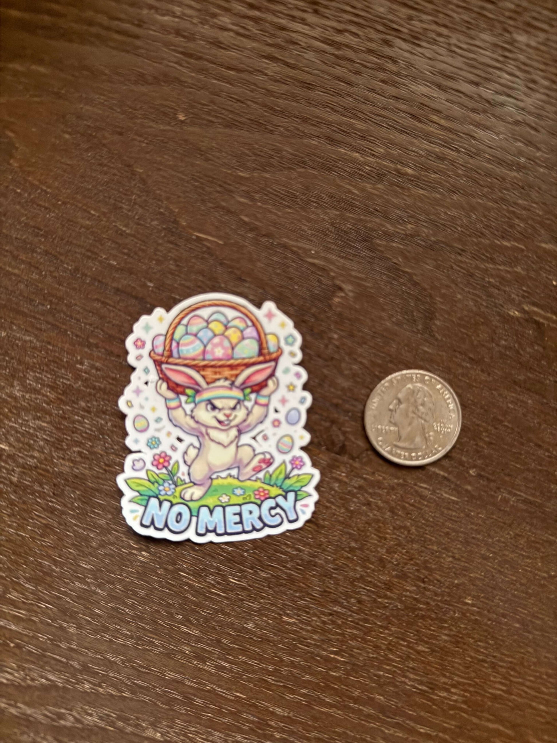 Colorful sticker with text 'NOMERCY!' next to a coin on a wooden surface