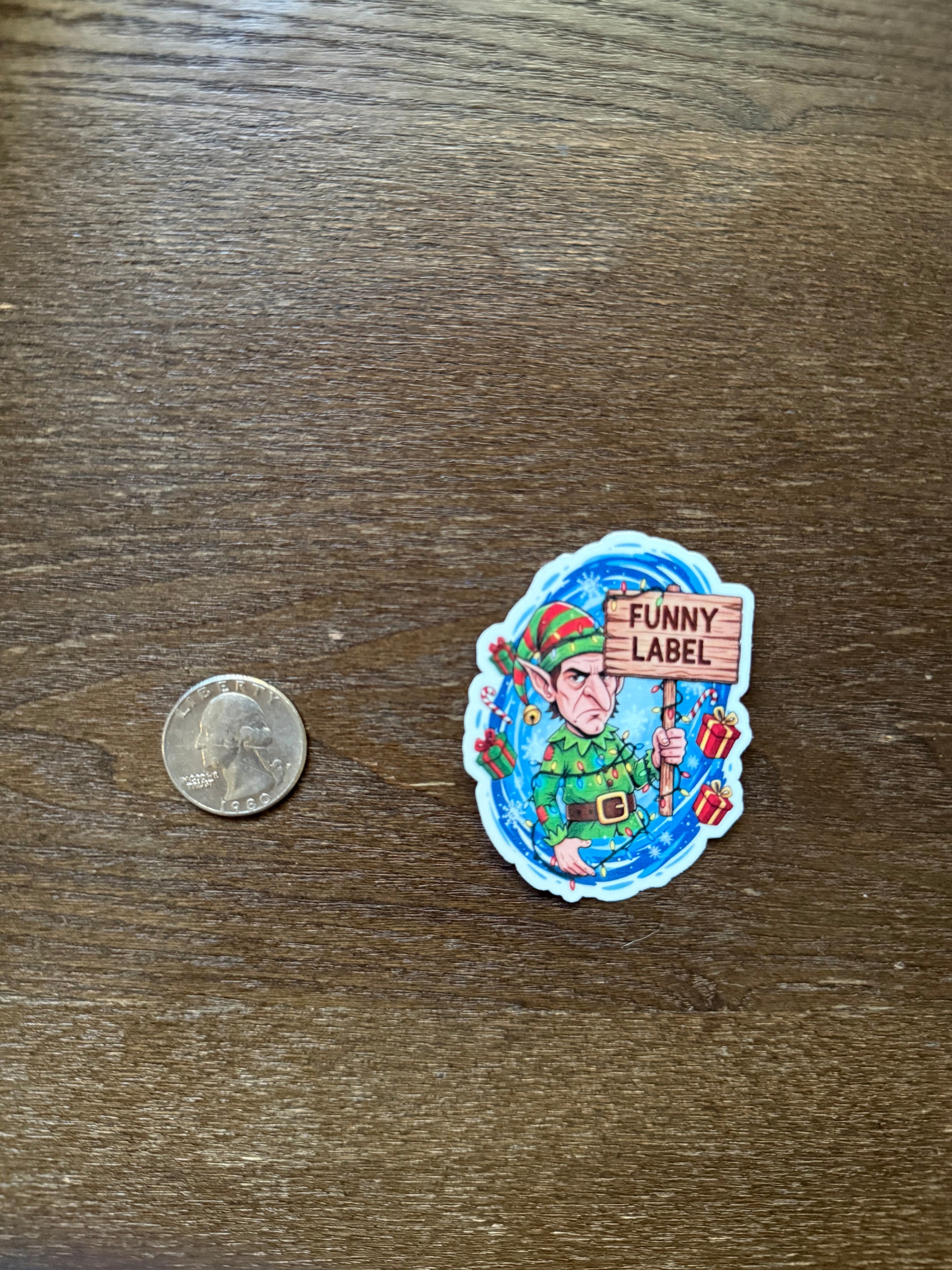 Colorful sticker with cartoon character and 'Funny Label' text on a wooden surface, next to a quarter for scale.