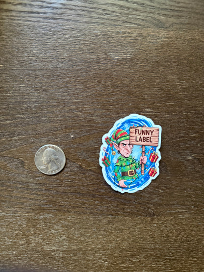Colorful sticker with cartoon character and 'Funny Label' text on a wooden surface, next to a quarter for scale.