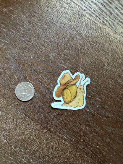 Snail-shaped sticker on a wooden surface with a coin for scale