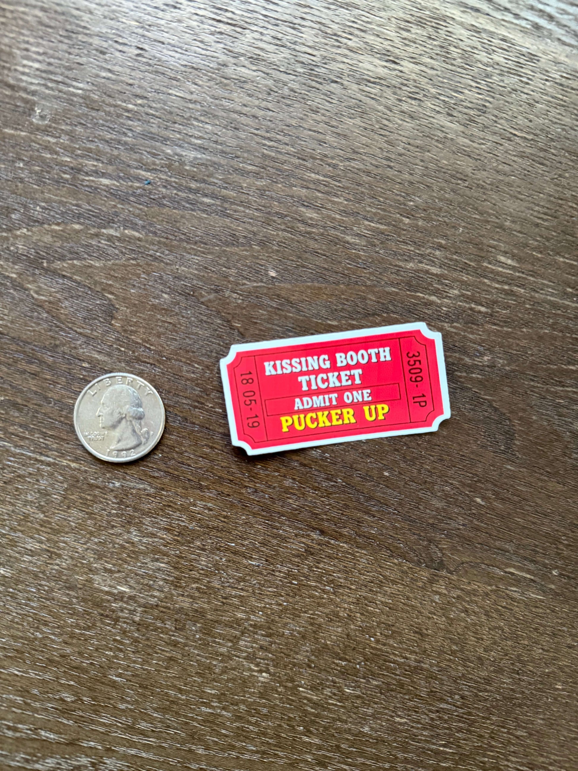 Red and white ticket-like card on a wooden surface with a coin for scale.