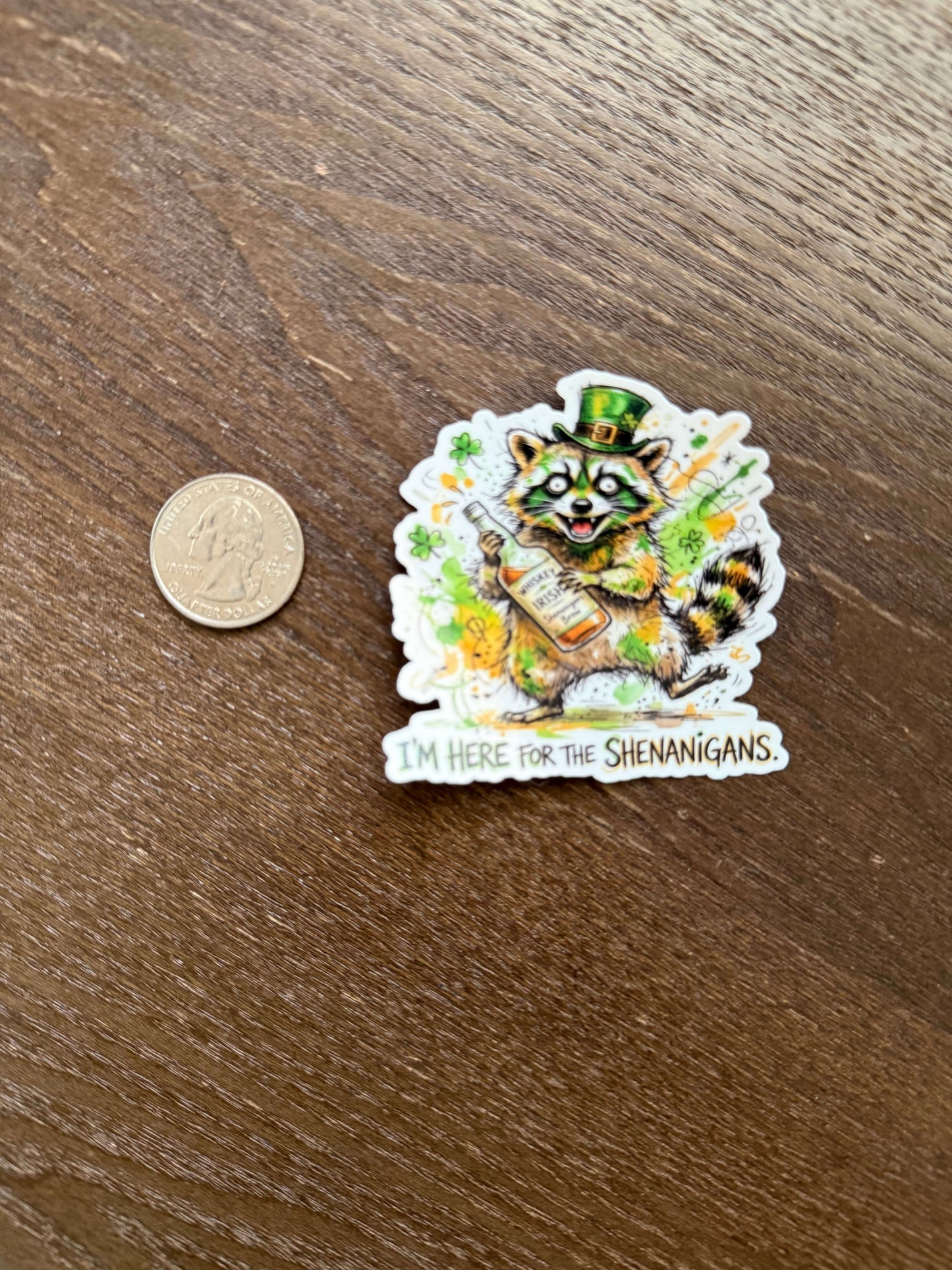 Sticker with a cat design on a wooden surface next to a coin for scale.