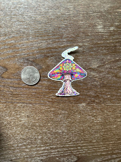 Colorful mushroom-shaped sticker next to a quarter on a wooden surface