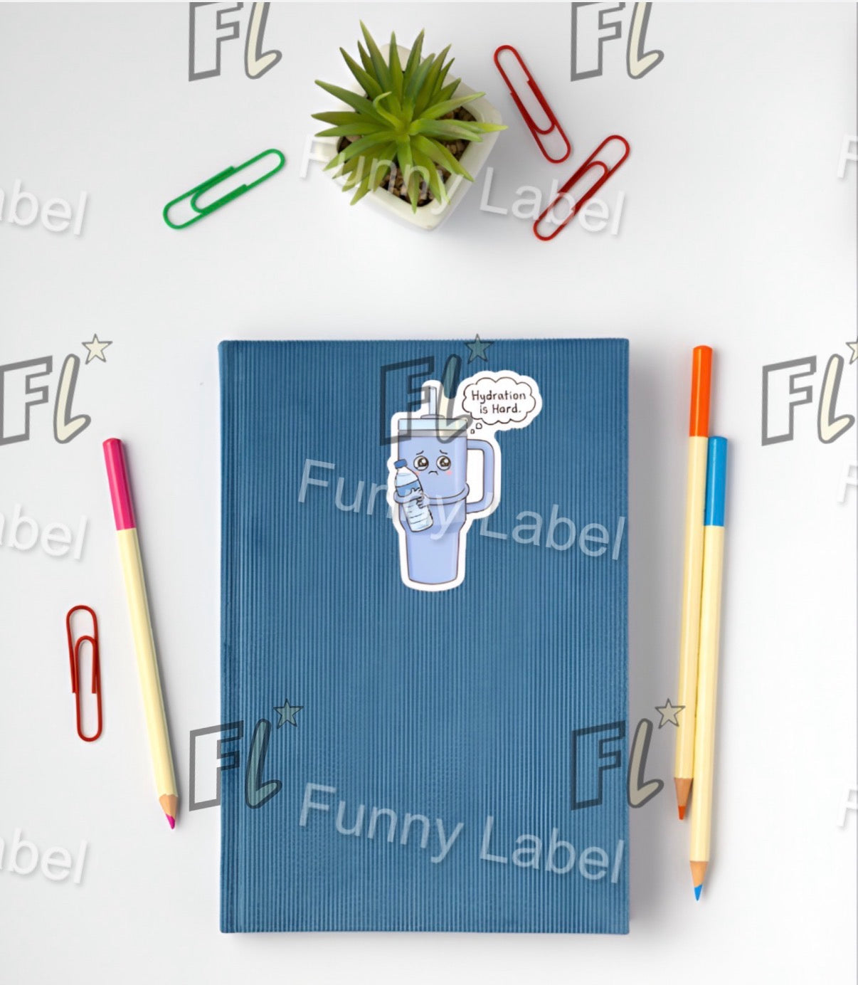 Blue notebook with a cartoon water bottle sticker, surrounded by pens and paper clips on a white background with 'FL' branding.