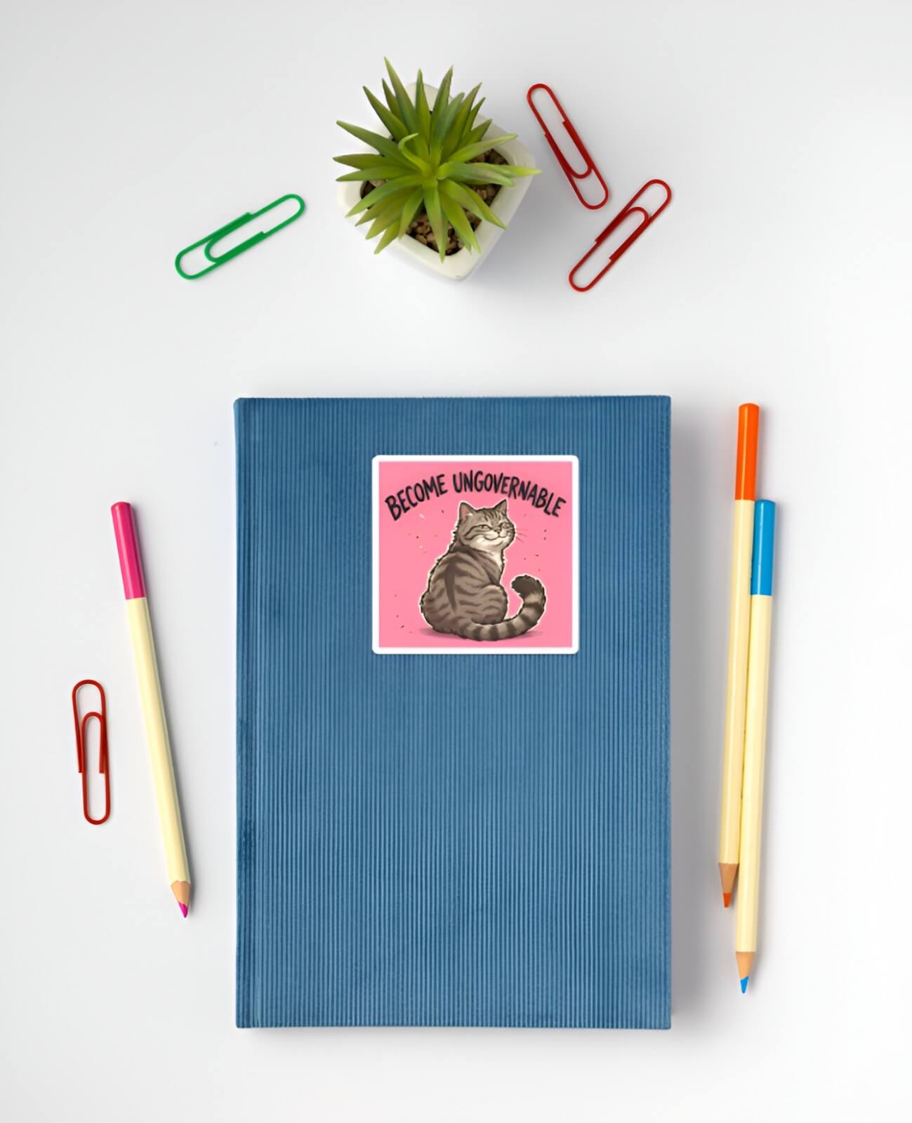 Blue notebook with a cat sticker and stationery items on a white background