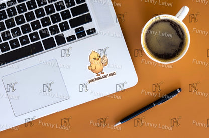 Laptop with a humorous sticker on the palm rest area, next to a coffee cup and pen on a wooden surface.