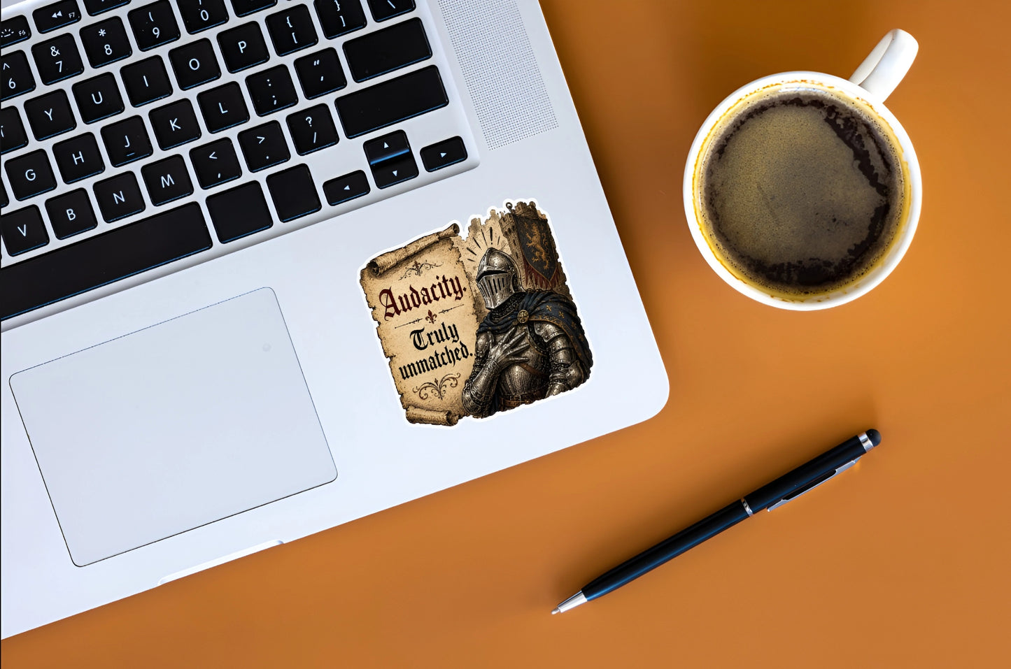 Audacity Truly Unmatched knight meme sticker displayed on a silver laptop beside coffee