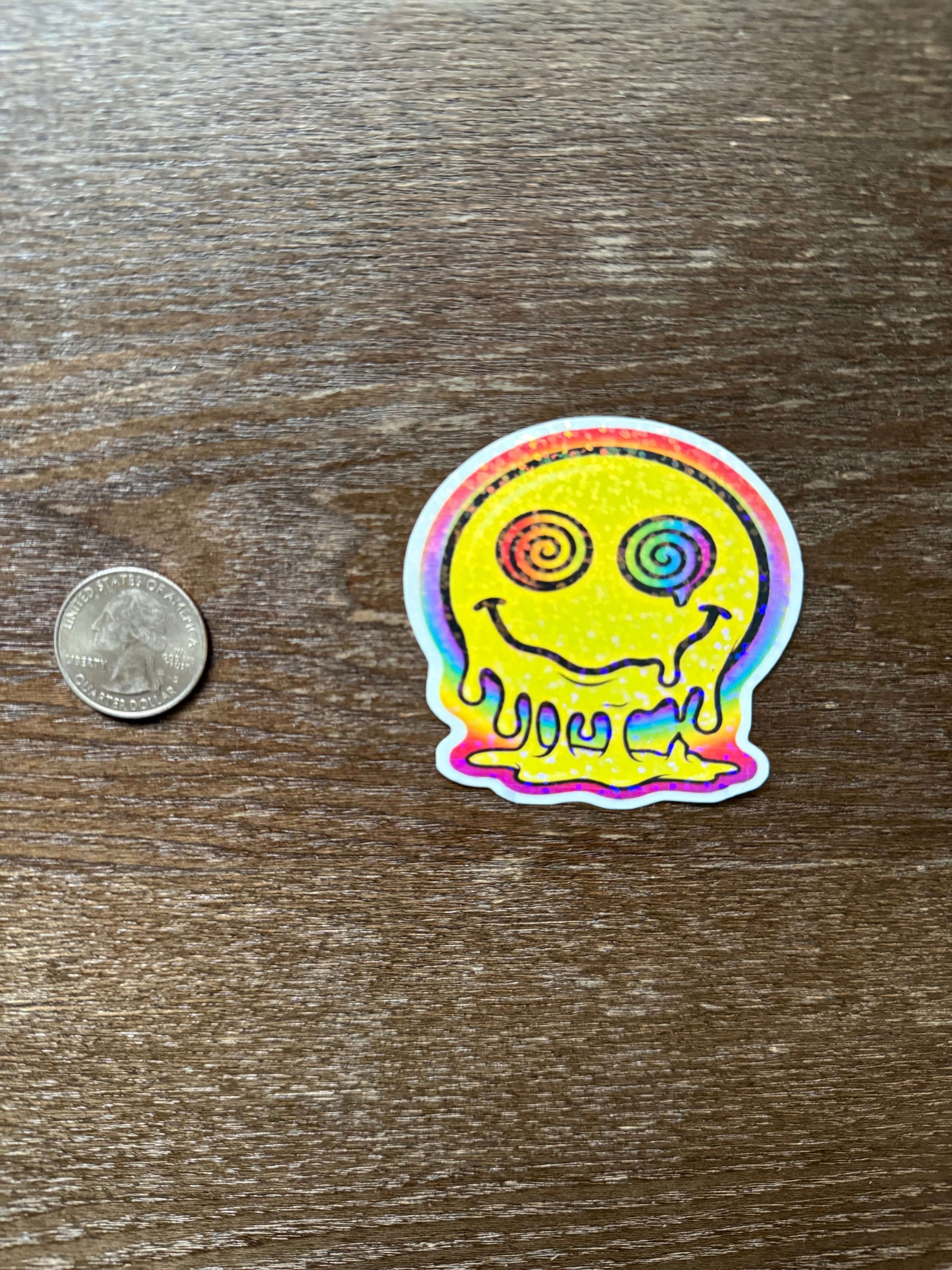 Colorful sticker with a design on a wooden surface next to a coin for scale.