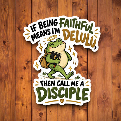 A die-cut sticker featuring a cartoon green frog carrying a Bible and backpack, with the text “IF BEING MEANS I’M FAITHFUL DELULU, THEN CALL ME A DISCIPLE,” shown on a brown wood plank background.