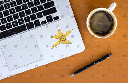 Laptop with a star sticker, pen, and coffee cup on a brown surface