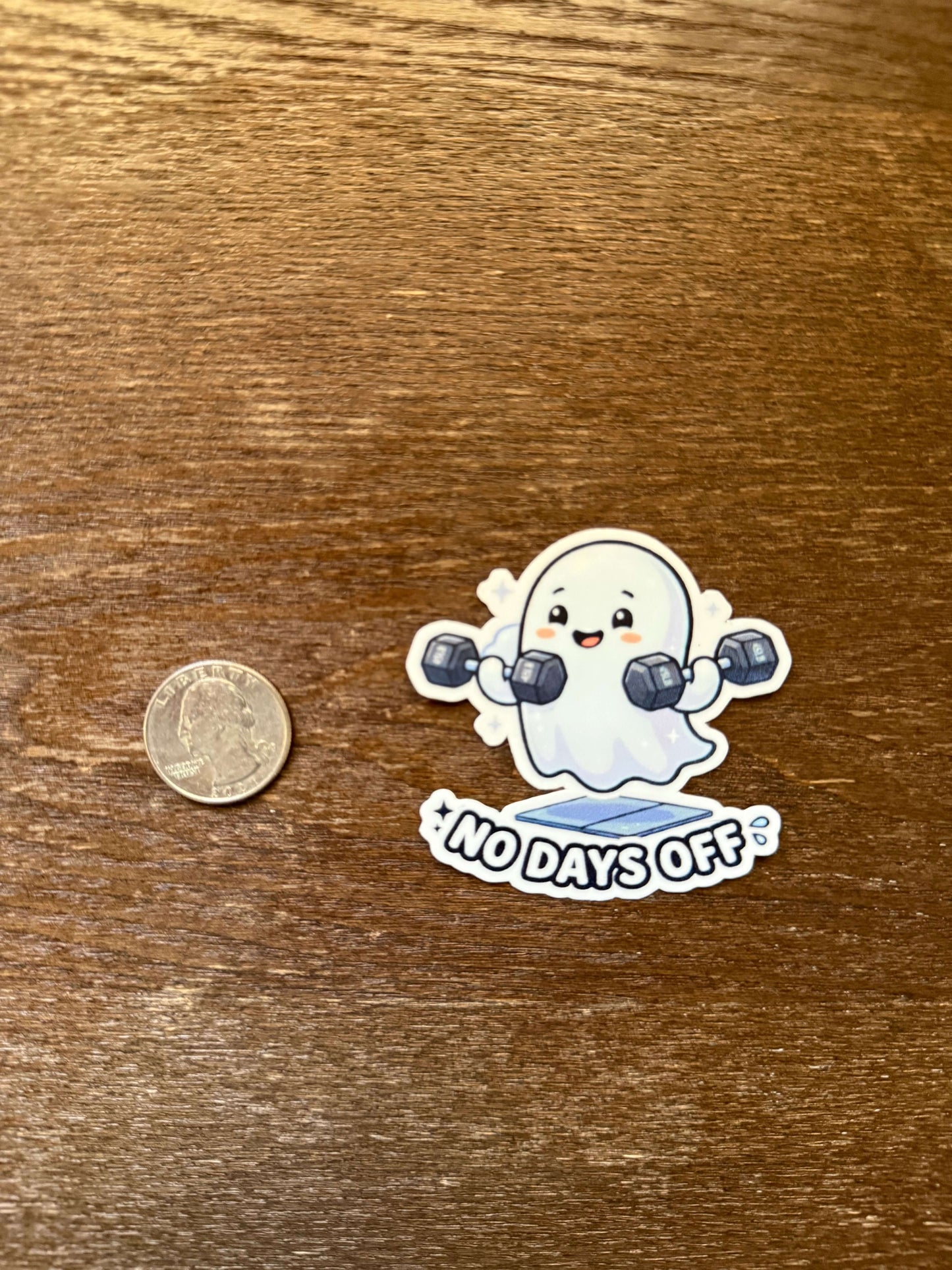 Sticker of a cartoon character with '100 days off' text on a wooden surface with a coin for scale.