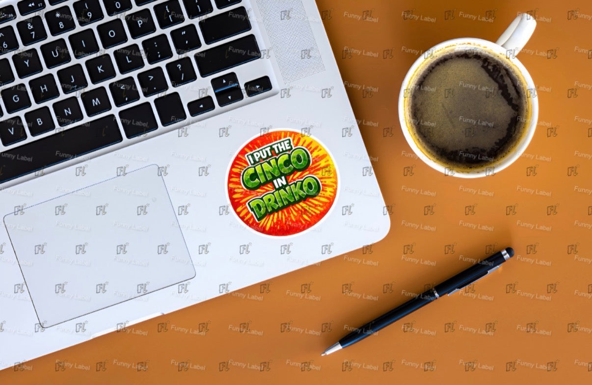 Laptop with a sticker on a desk next to a cup of coffee and a pen