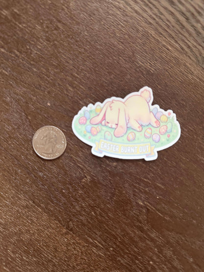 Sticker of a bear with rainbow elements on a wooden surface next to a coin for scale.