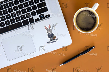 Laptop with a cartoon rabbit sticker on a brown surface with a coffee cup and pen.