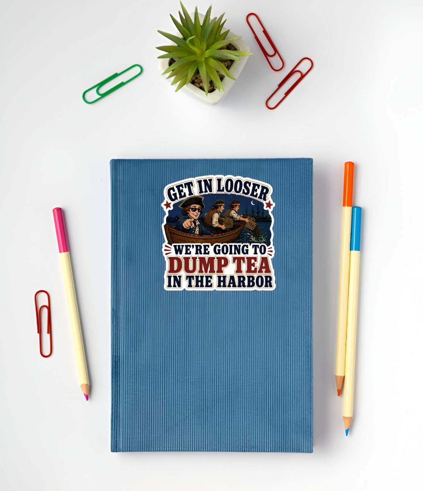 Blue notebook with a graphic design on a white surface with stationery items.