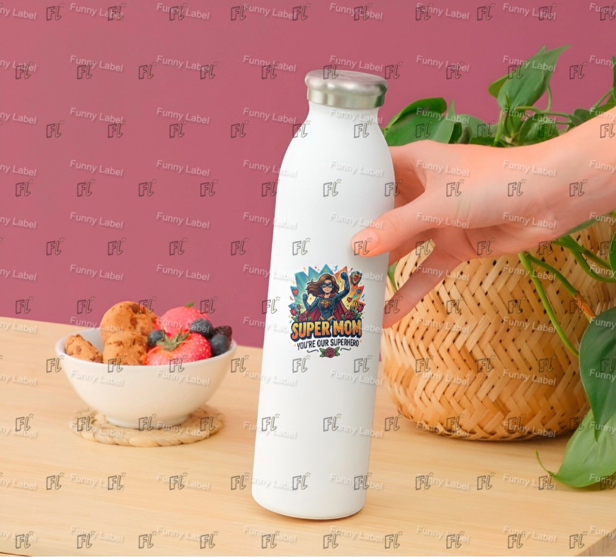 White water bottle with superhero design held by a hand on a table with fruit and cookies.