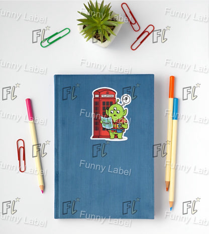 Blue notebook with a sticker of a green alien character on a white background with stationery items.