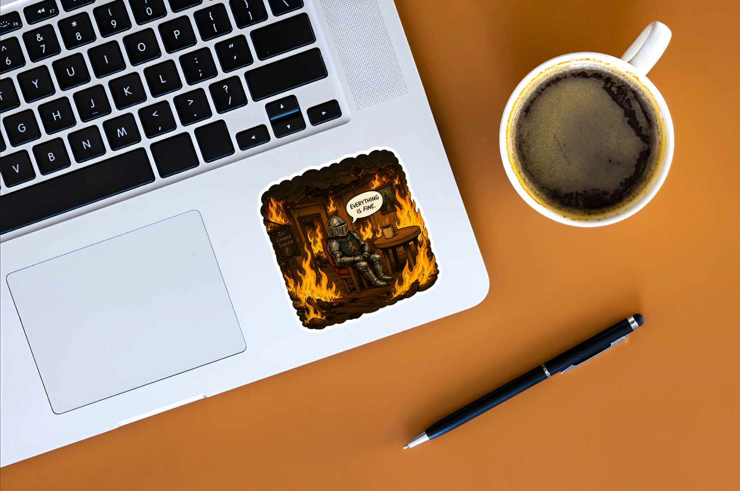 Everything Is Fine knight meme sticker displayed on a silver laptop beside coffee