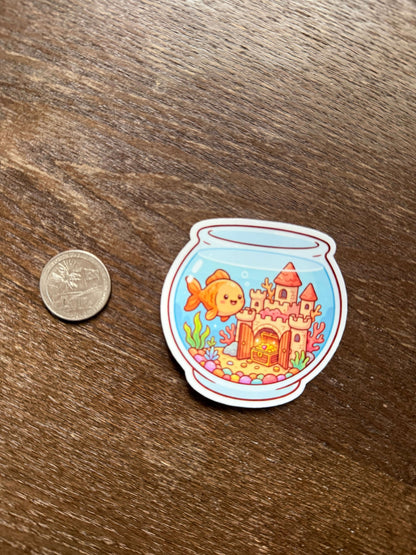 Sticker of a fish and castle design on a wooden surface with a coin for scale.