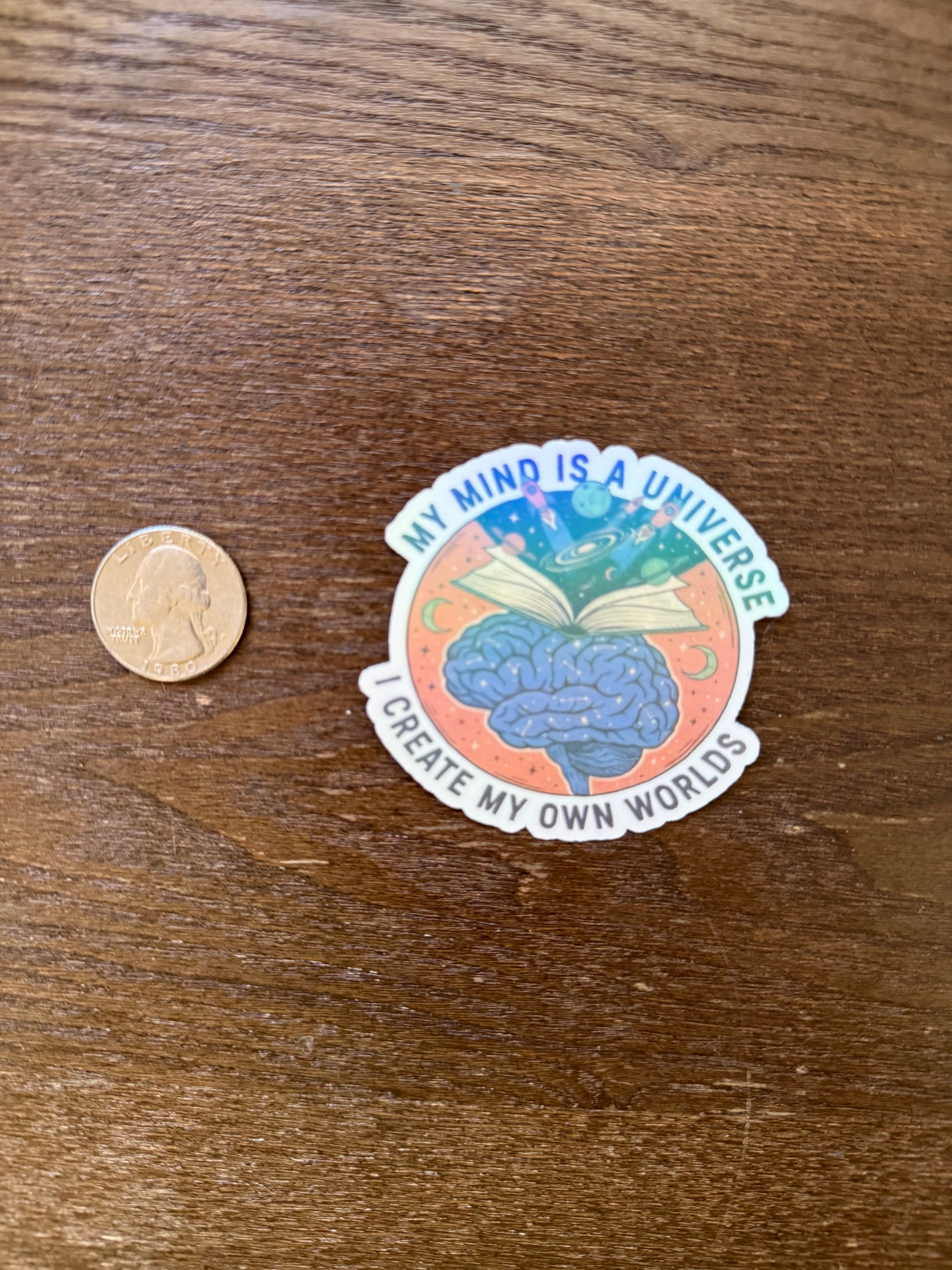 Sticker with brain graphic and text on a wooden surface with a coin for scale