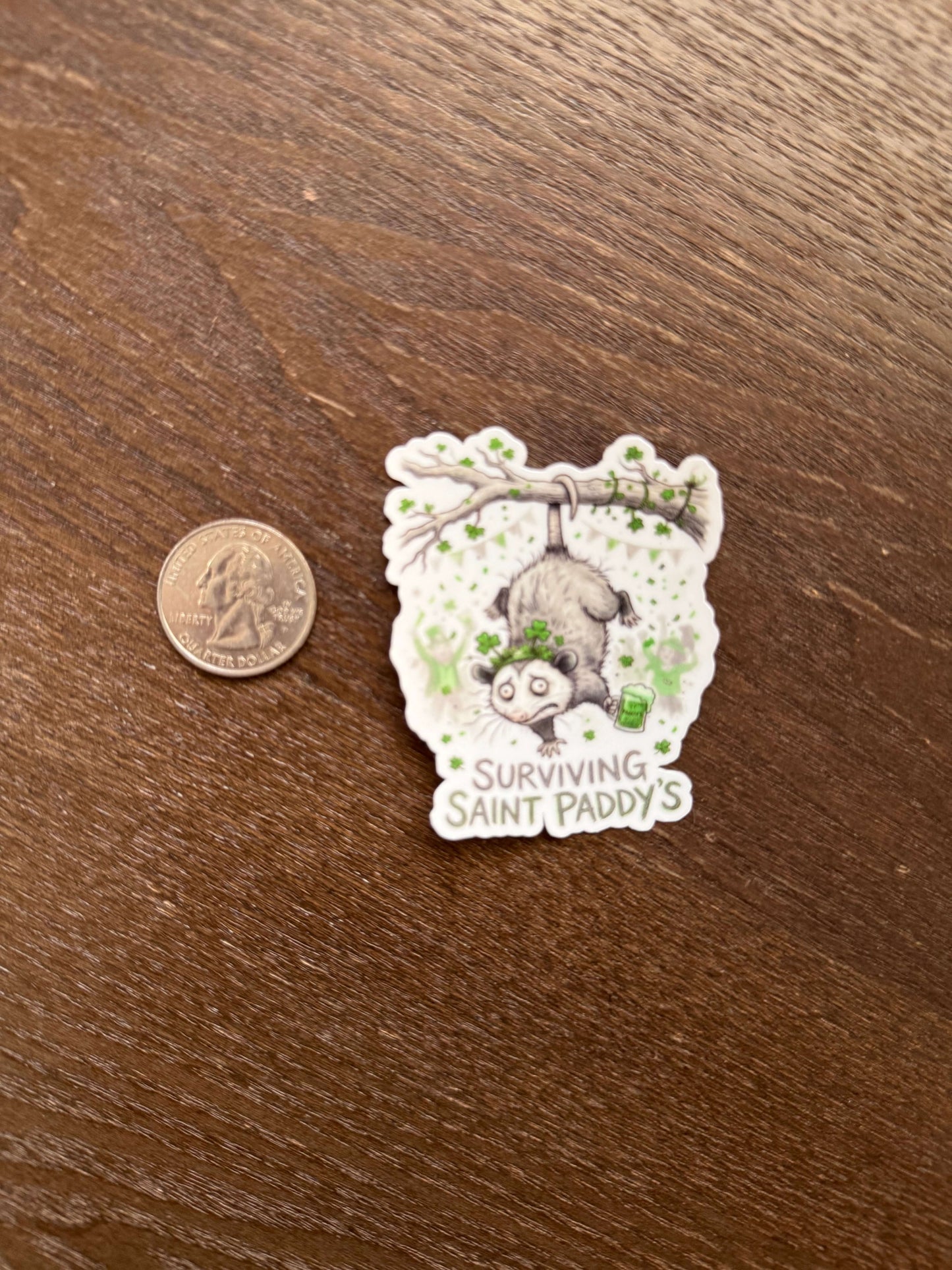 Sticker of a sloth on a branch with text, placed next to a coin on a wooden surface.