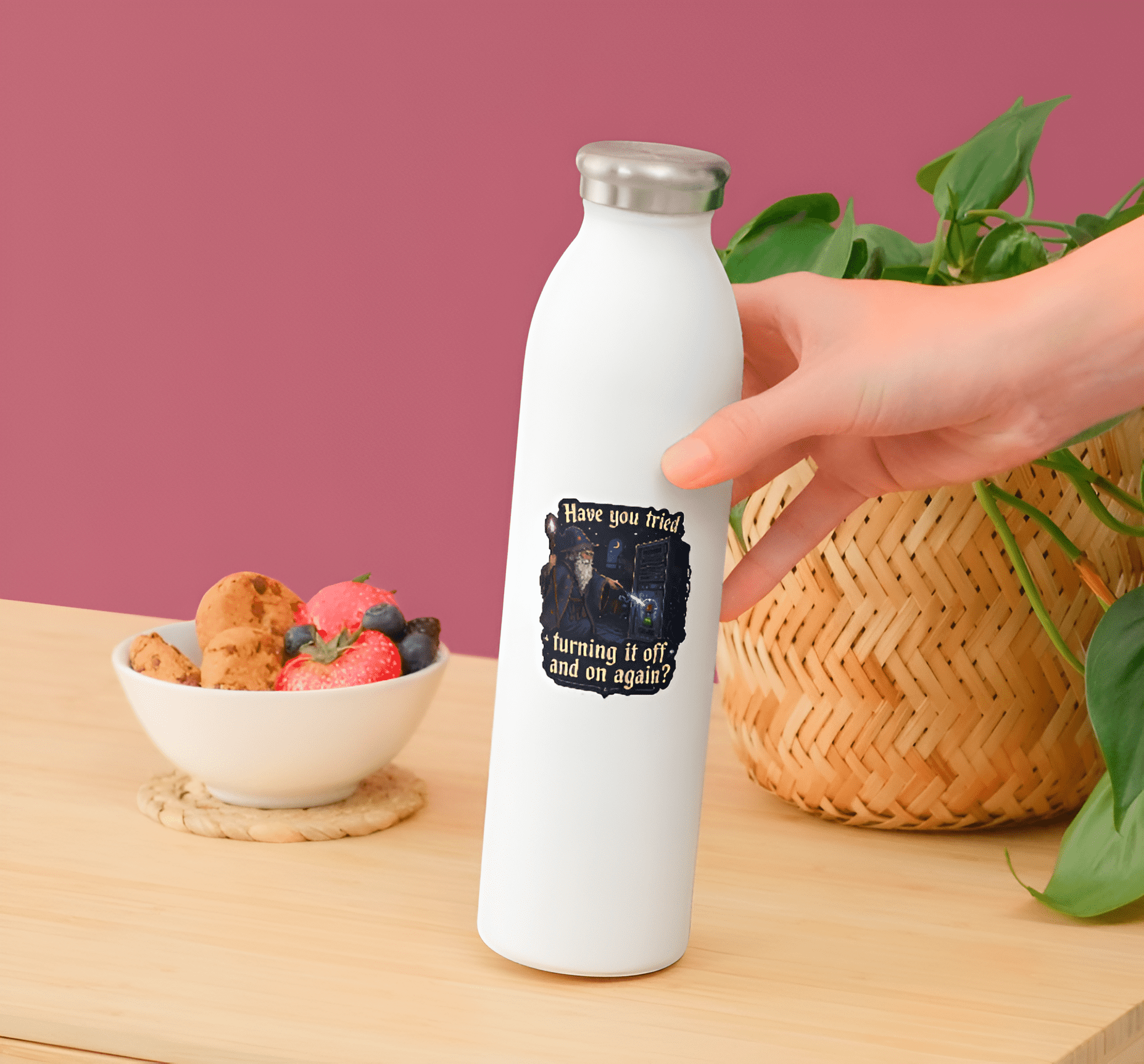 White water bottle with a design on a wooden table with a bowl of snacks and a plant.