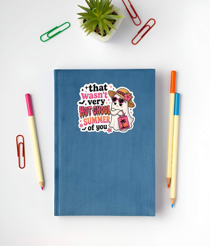 Blue notebook with a Funny Hot Ghoul Summer ghost sticker, cute Halloween beach vinyl decal, tropical ghost in straw hat and pink heart sunglasses with sunset beach tote bag graphic.on a white background with stationery items