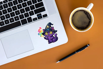 Laptop with a colorful sticker on an orange surface next to a cup of coffee and pen