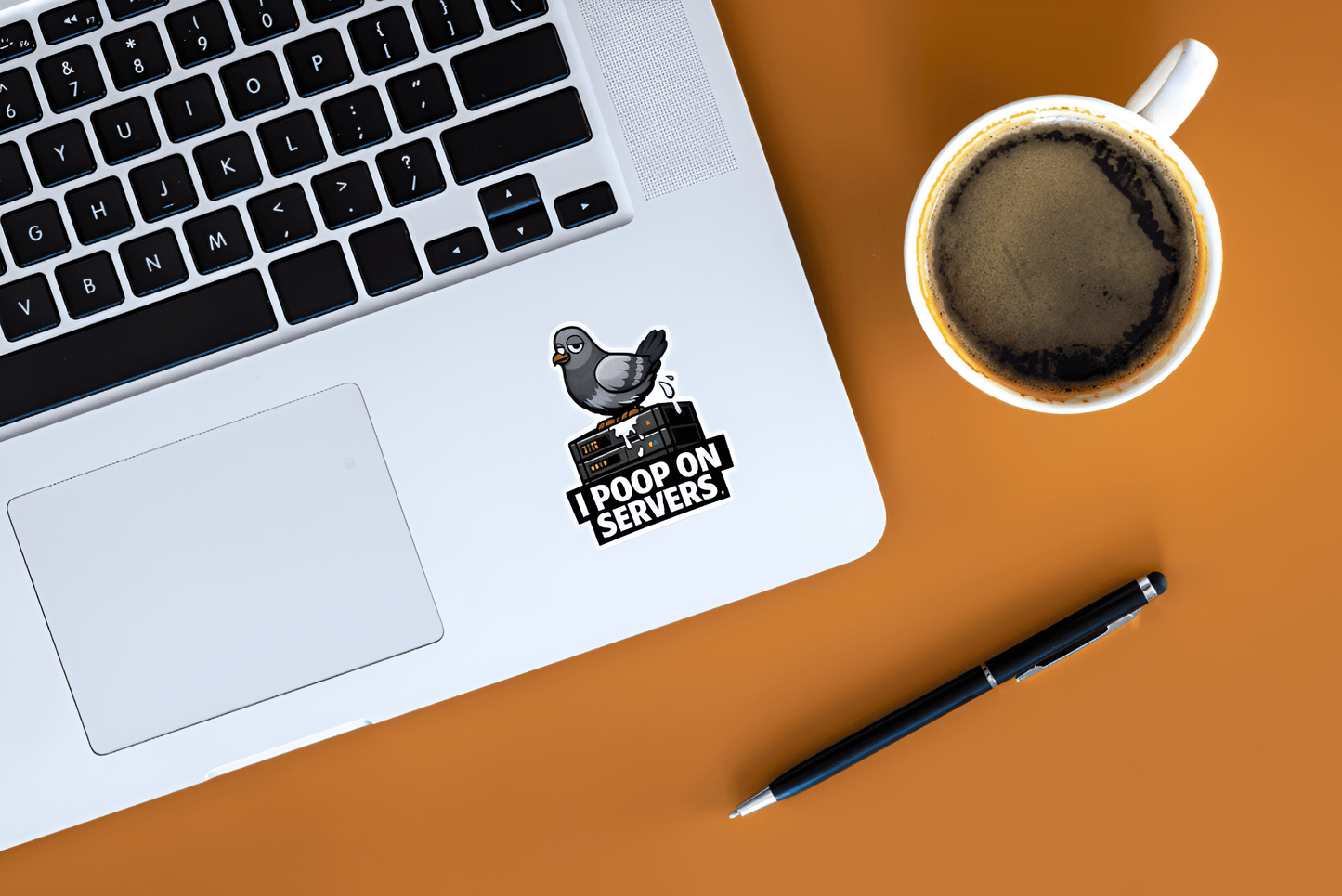 Laptop with 'I Poop on Servers' sticker, coffee cup, and pen on a brown surface