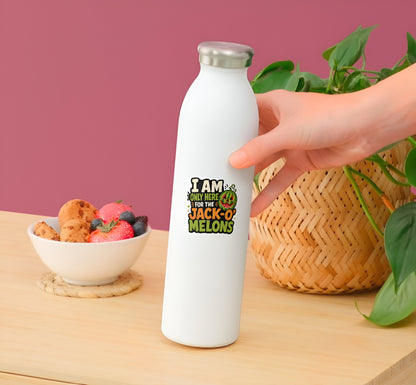 White water bottle with a cFunny Summerween watermelon sticker by a hand on a wooden surface with a bowl of snacks and plant in the background.