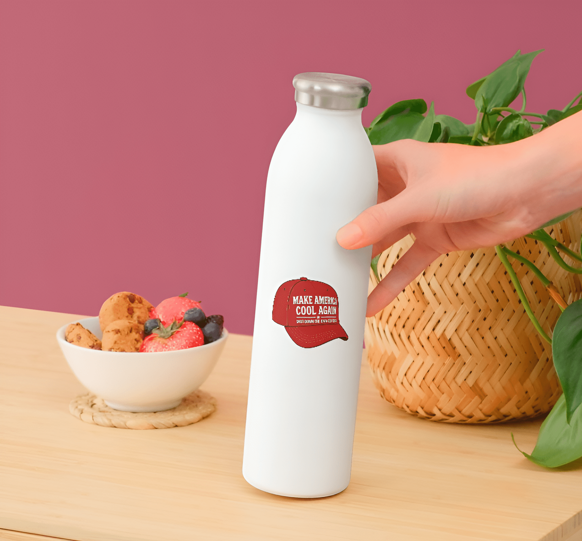 White water bottle with red label held by a hand on a wooden table with snacks and a plant.