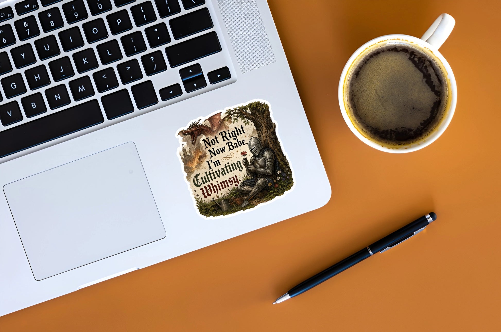 Not Right Now Babe I’m Cultivating Whimsy knight sticker displayed on a silver laptop beside coffee